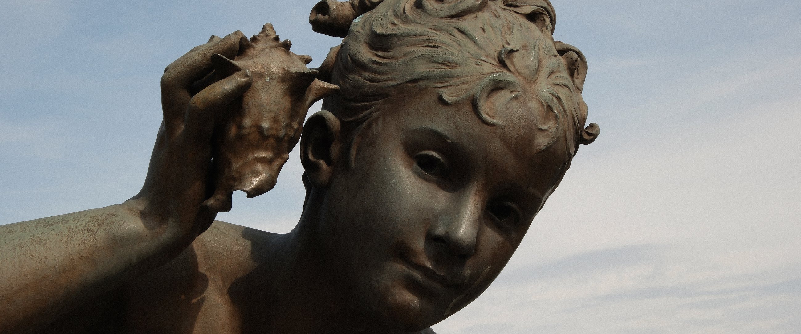 Bronze statue of a child listening to a seashell